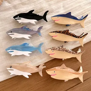 Collection of colorful shark shaped acetate hair claws on a textured surface