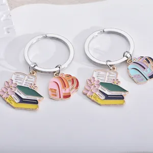 Detailweergave van geëmailleerde sleutelhangers met schoolthema, boek en rugzak.