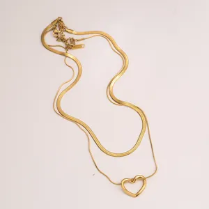 Dettaglio di collana a doppio strato con ciondolo a cuore dorato e catena a serpente