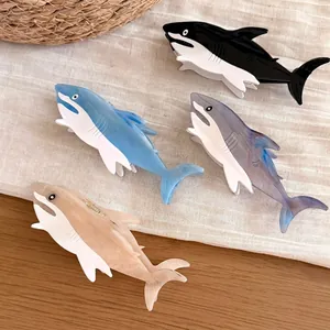 Macro view of four colorful shark-shaped acetate hair claw clips for thick hair.