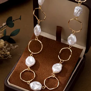 Macro view of a minimalist baroque pearl necklace with irregular gold circular links