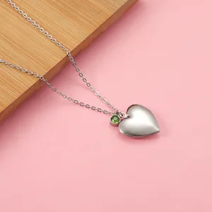 Detailed view of silver heart locket necklace with green zircon gemstone pendant