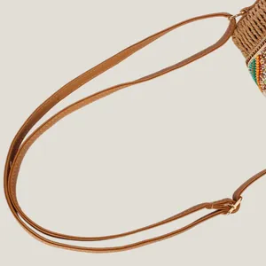 Close-up of a brown leather strap on a colorful woven paper rope shoulder bag