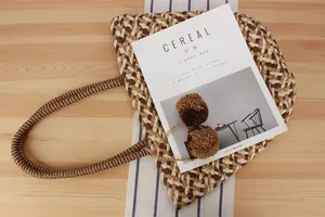 Detailed look at large handwoven paper rope shoulder bag with decorative pom-pom charms