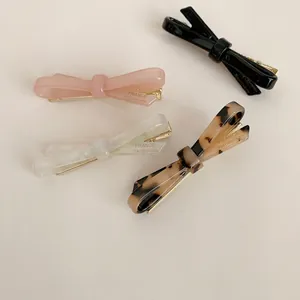 Close-up of four colorful acetate bow hair clips with elegant patterns and textures