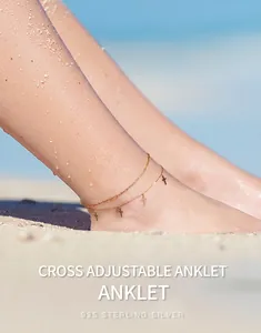 Detailed shot of a double-layered cross anklet made of 925 sterling silver on beach