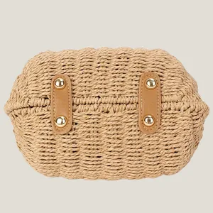Bottom view of a woven paper rope crossbody bag with durable protective metal studs