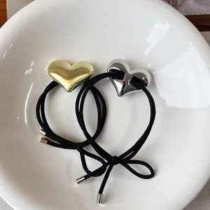 Detail of minimalist gold and silver metallic heart charms on elastic black hair ties