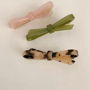 Handmade acetate bow hair clips in pink, olive green, and tortoiseshell patterns