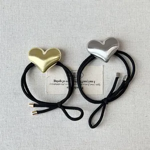 Close-up of minimalist metallic heart hair ties in gold and silver finishes.