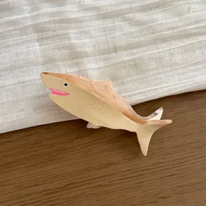 Detailed view of a shark-shaped acetate hair claw clip resting on a wooden background
