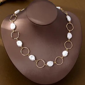 Detailed macro view of a baroque faux pearl and gold ring necklace on a brown bust