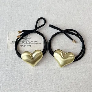 Detailed view of high-quality gold heart alloy hair ties on a textured cream background