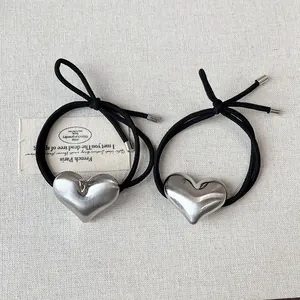 Set of two minimalist black elastic hair ties featuring brushed silver alloy heart pendants.