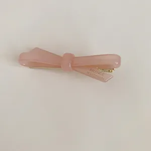Detailed macro view of an elegant pink acetate bow hair clip with handmade text