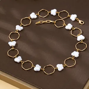 Minimalist gold chain necklace with baroque butterfly faux pearls on brown background.