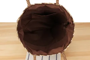 Detailed view of large woven straw bag interior with brown lining and zipper pocket
