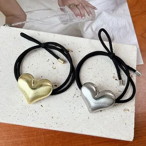 Detailed macro view of gold and silver metallic heart hair ties with elegant brushed finish.