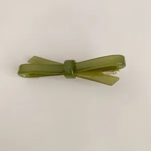 Close-up of elegant olive green bow acetate hair clip with gold metal fastener