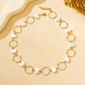 Close-up detail of a minimalist gold necklace with white baroque butterfly pearls