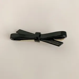 Close-up of a glossy black acetate bow hair clip on a neutral background