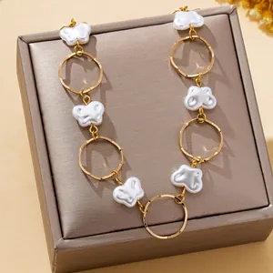 Detail view of a baroque faux pearl necklace with elegant gold-toned metal rings on a gift box