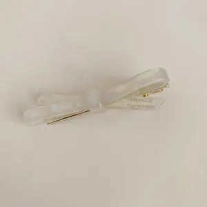 Close-up of pearl white acetate bow hair clip with France Handmade engraving detail