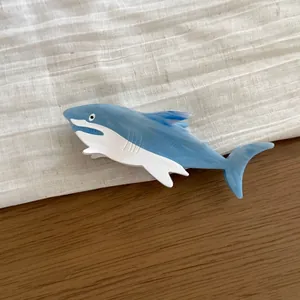 Macro detail of a creative blue and white shark-shaped acetate hair claw clip on linen