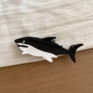 Detailed side view of a large black and white shark-shaped acetate hair claw clip for women