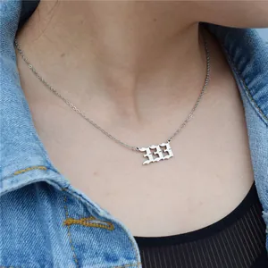 Close-up shot of a silver stainless steel angel number 333 necklace worn by a model.