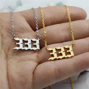 Close-up detail of gold and silver stainless steel angel number 333 necklaces held by a hand