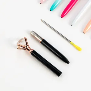 Elegant black metal ballpoint pen with a large rose gold diamond top on white background.