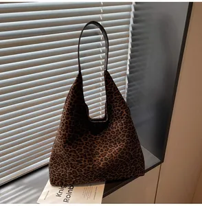 Dettaglio di una grande borsa tote in pelle scamosciata leopardata contro persiane.