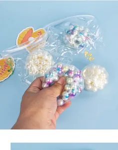 Detail view of a hand squeezing a sensory fidget toy filled with colorful pearl beads