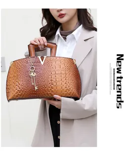 Elegant brown crocodile embossed leather handbag with V metal accent held by model