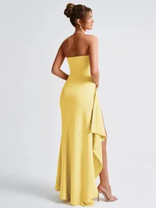 Rear view of an elegant yellow strapless evening dress with side slit and irregular hem.