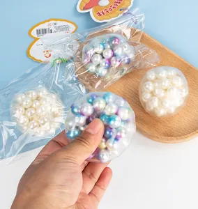 Close-up view of a hand squeezing a colorful iridescent pearl bead stress relief ball toy.