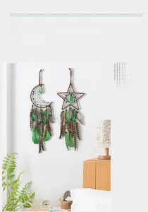 Detalle de atrapasueños de estrella y luna con plumas verdes colgados en la pared