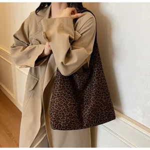 Modella che indossa un trench beige e una grande borsa tote scamosciata leopardata.