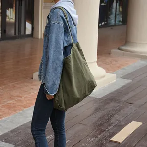 Detailed shot of an olive green canvas tote bag styled with a denim jacket outdoors