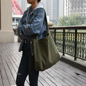 Large olive green minimalist canvas tote bag carried by a model in an urban setting