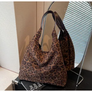 Primo piano di una borsa tote in pelle scamosciata maculata vicino a uno specchio