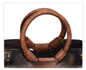 Close-up detail of retro textured brown leather round handles on a vintage handbag