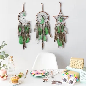 Set of three star, moon, and round green feather dreamcatchers hanging on a white wall