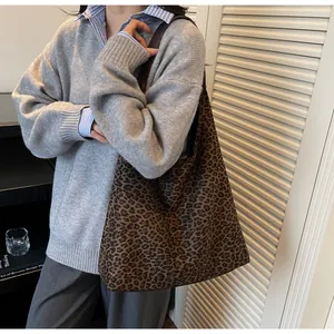 Dettaglio di una borsa tote in pelle scamosciata leopardata indossata da modello