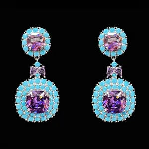 Macro detail of luxury princess-cut purple zircon earrings with turquoise beads.