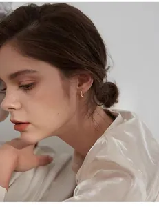 Close-up view of elegant gold Mobius hoop earrings worn by a model in soft lighting