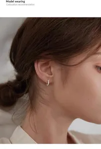 Detailed view of a minimalist sterling silver Mobius hoop earring worn by an Asian model