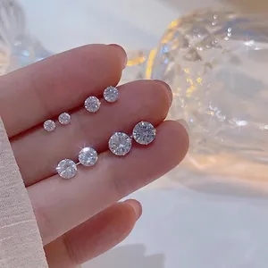Mano che tiene scintillanti orecchini a lobo in argento 925 e zirconi di varie misure