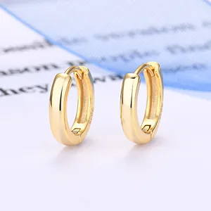 Primo piano di orecchini a cerchio in argento 925 placcato oro su sfondo minimalista